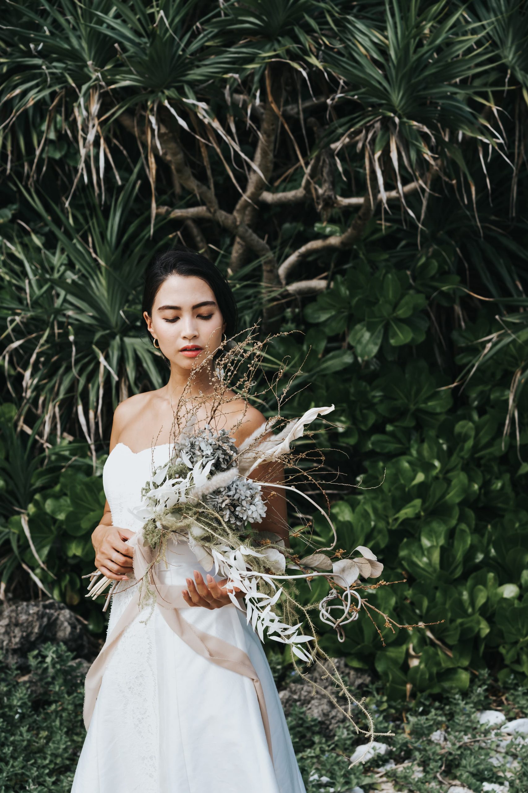沖縄の自然の中でブーケを抱える花嫁
