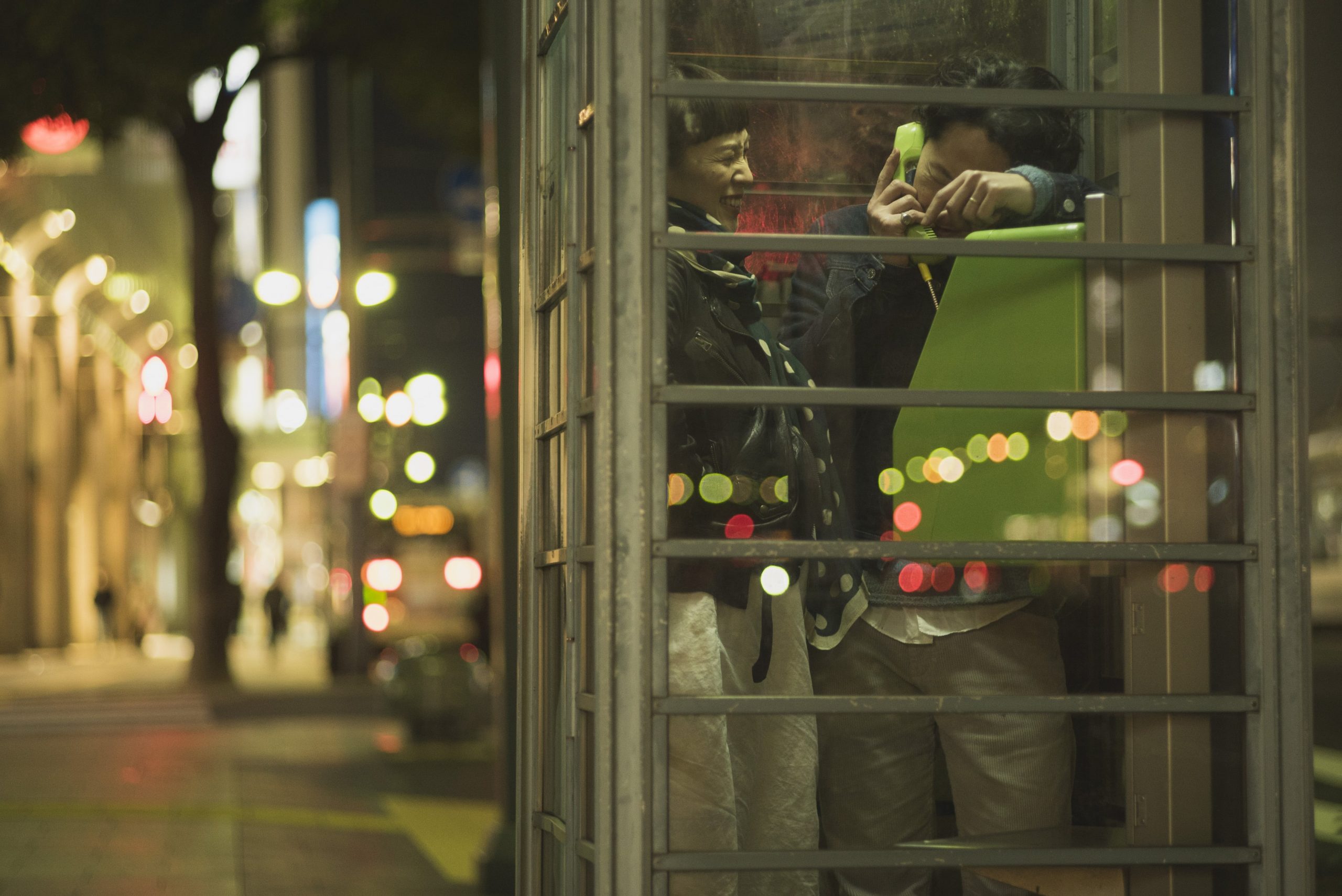 夜の街中の電話ボックスにいる新郎新婦