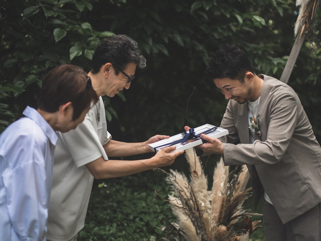 沖縄家族婚にて贈呈品を渡す新郎。